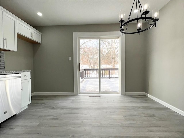 unfurnished dining area with a chandelier and light hardwood / wood-style flooring