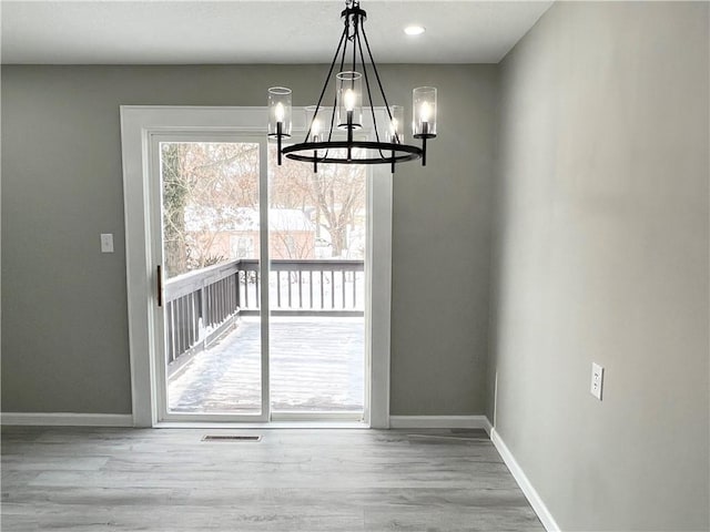 unfurnished dining area with hardwood / wood-style floors and a notable chandelier