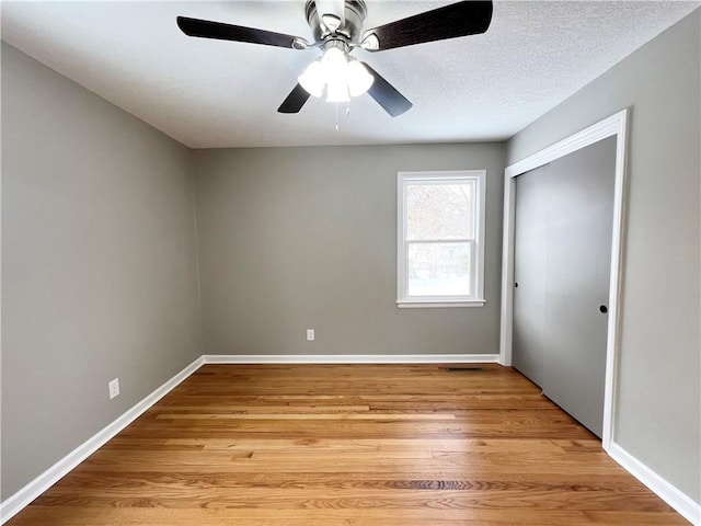 empty room featuring ceiling fan, a textured ceiling, and light wood-type flooring