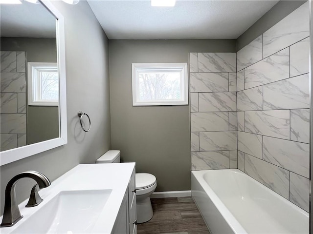 full bathroom featuring a wealth of natural light, toilet, tiled shower / bath, and wood-type flooring