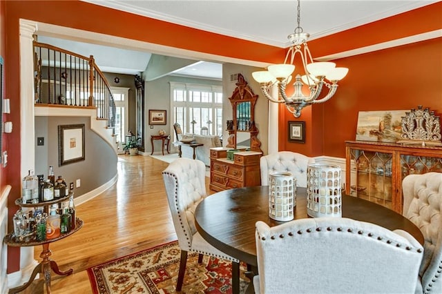 dining area with an inviting chandelier, crown molding, and light hardwood / wood-style flooring