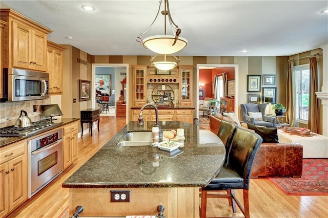 kitchen featuring pendant lighting, an island with sink, sink, a kitchen bar, and stainless steel appliances