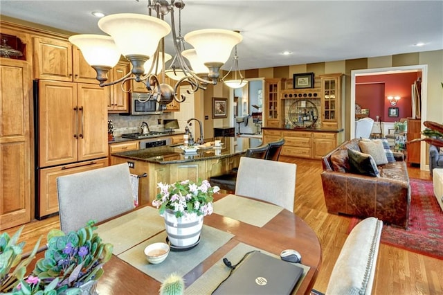 dining area with an inviting chandelier, sink, and light wood-type flooring