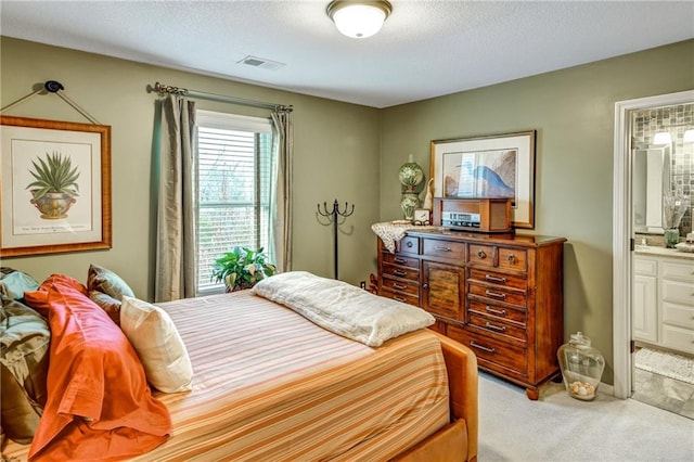 carpeted bedroom featuring ensuite bath and a textured ceiling