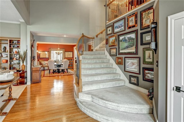 stairs with hardwood / wood-style floors, crown molding, and a towering ceiling