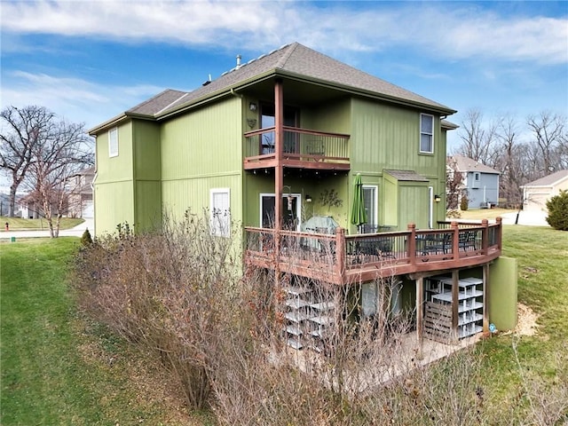 rear view of house featuring a yard and a balcony