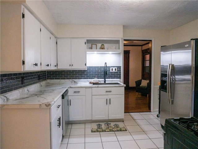 kitchen featuring white cabinets, appliances with stainless steel finishes, sink, and light stone counters