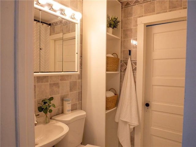 bathroom featuring toilet, tile walls, sink, and tasteful backsplash