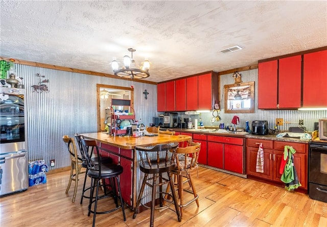 kitchen with refrigerator, a textured ceiling, a notable chandelier, and light hardwood / wood-style flooring