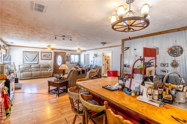 dining space featuring a textured ceiling, light hardwood / wood-style floors, crown molding, and ceiling fan with notable chandelier