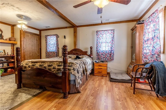 bedroom with ceiling fan, light wood-type flooring, crown molding, and a textured ceiling