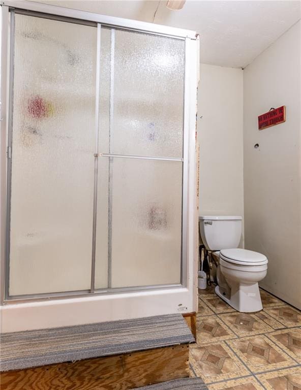 bathroom with a shower with shower door and toilet