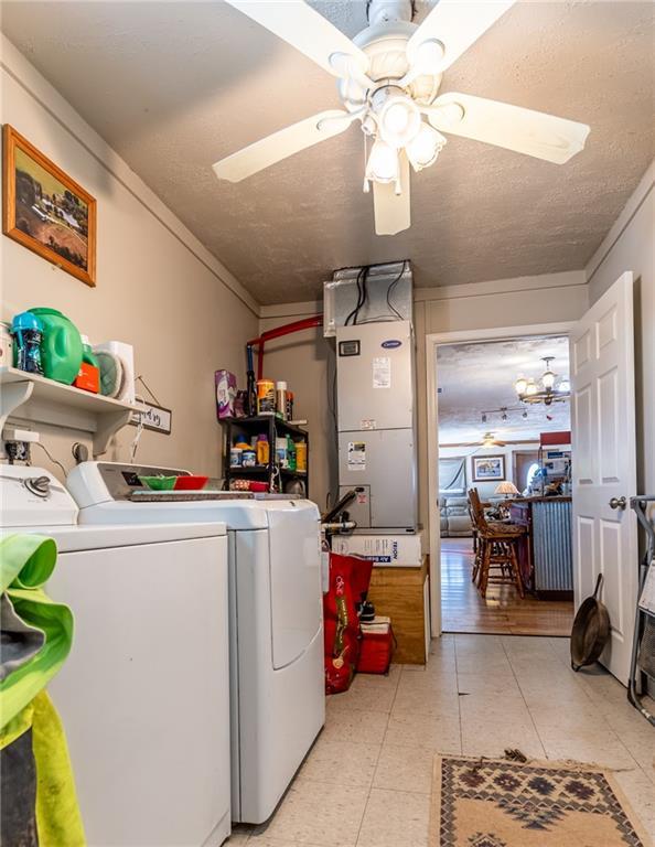 laundry area with a textured ceiling, washing machine and clothes dryer, ceiling fan, ornamental molding, and heating unit