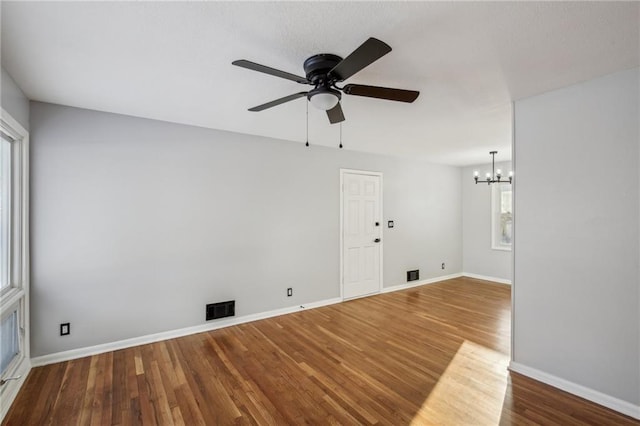 unfurnished room featuring ceiling fan with notable chandelier and hardwood / wood-style floors