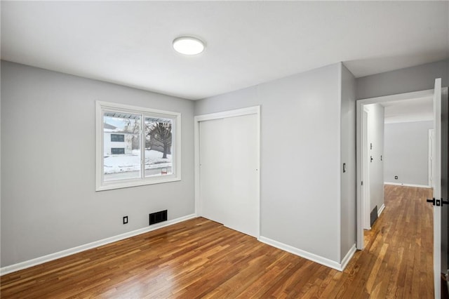 unfurnished bedroom featuring a closet and hardwood / wood-style flooring