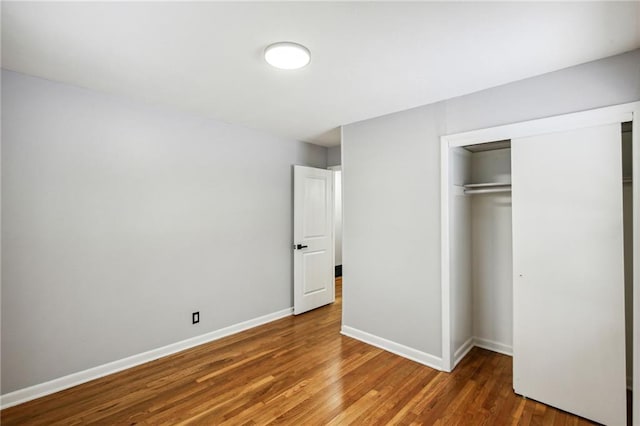 unfurnished bedroom with a closet and dark wood-type flooring