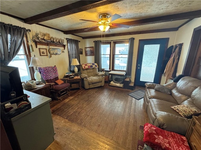 living room with beam ceiling, ceiling fan, wooden walls, and wood-type flooring