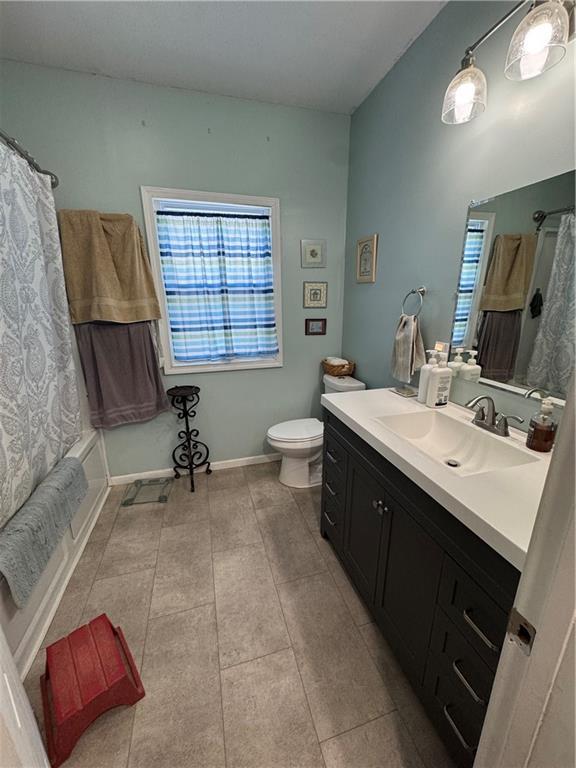 full bathroom with tile patterned floors, shower / tub combo with curtain, vanity, and toilet