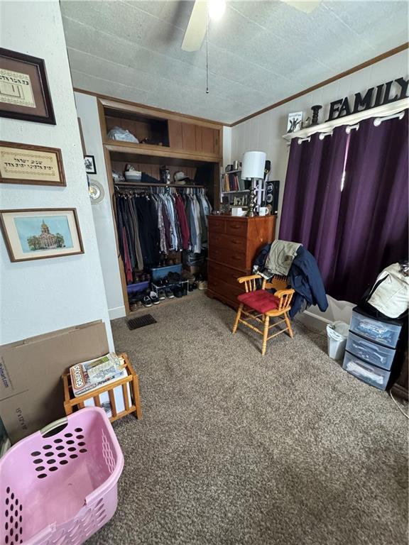 bedroom with carpet, ornamental molding, a textured ceiling, ceiling fan, and a closet