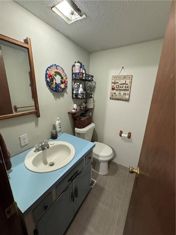 bathroom featuring vanity, toilet, and a textured ceiling