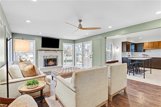 living room with a fireplace, dark hardwood / wood-style flooring, and ceiling fan