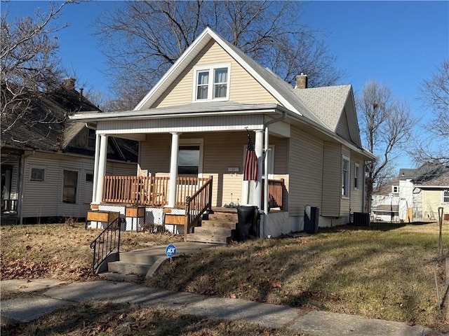 bungalow-style home with cooling unit, a porch, and a front yard