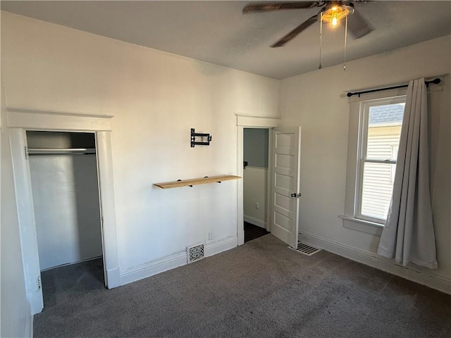 unfurnished bedroom with dark colored carpet, a closet, and ceiling fan