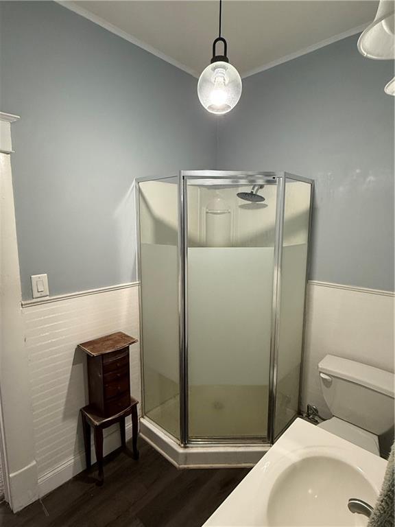 bathroom with sink, hardwood / wood-style flooring, toilet, ornamental molding, and walk in shower