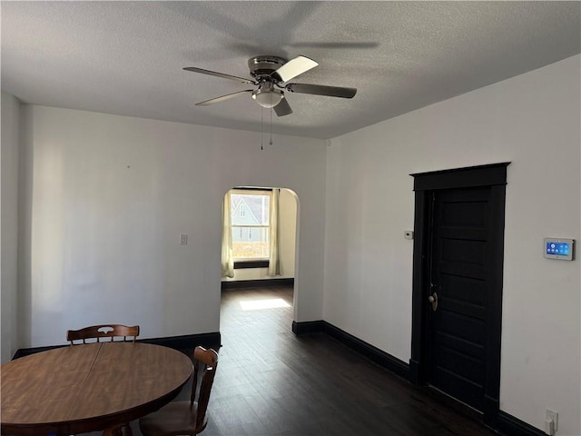 dining space featuring a textured ceiling, ceiling fan, and dark wood-type flooring