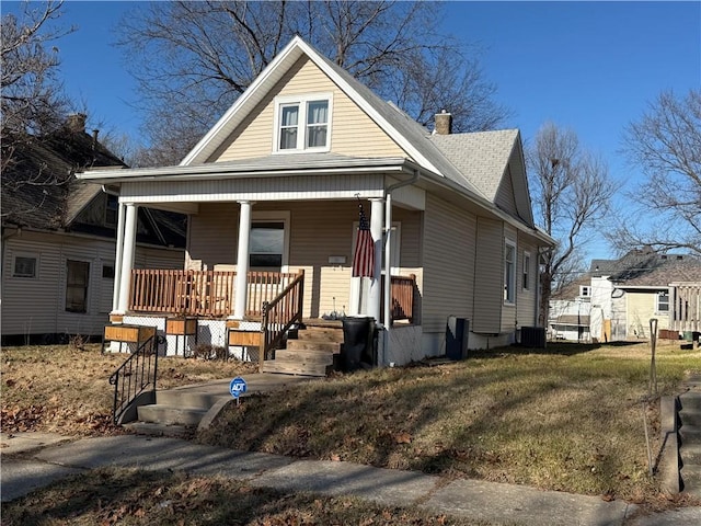 bungalow-style home with central AC, covered porch, and a front yard