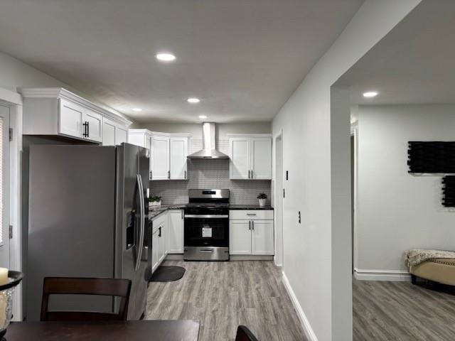 kitchen with white cabinets, decorative backsplash, stainless steel appliances, and wall chimney exhaust hood