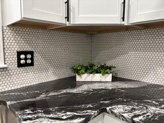 interior details featuring backsplash and white cabinetry