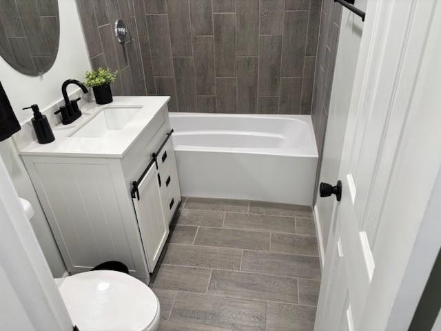 full bathroom with vanity, tiled shower / bath combo, and toilet