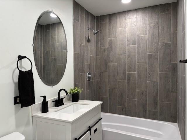 full bathroom featuring vanity, tiled shower / bath combo, and toilet