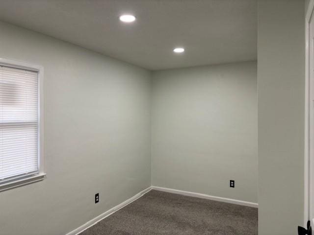 spare room with dark colored carpet