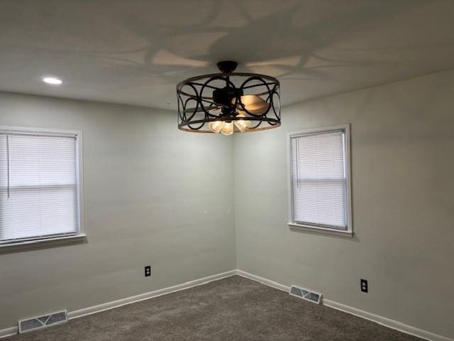 empty room featuring ceiling fan and dark colored carpet