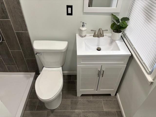 bathroom featuring vanity, toilet, and walk in shower