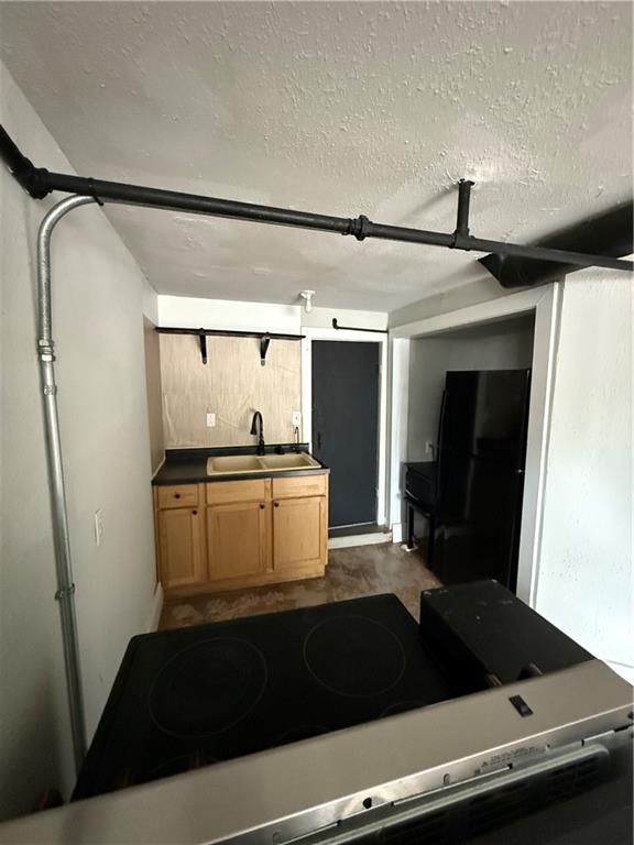 211 N Mulberry St, Maryville, MO 64468 - kitchen featuring freestanding refrigerator, stove, a textured ceiling, and light brown cabinetry