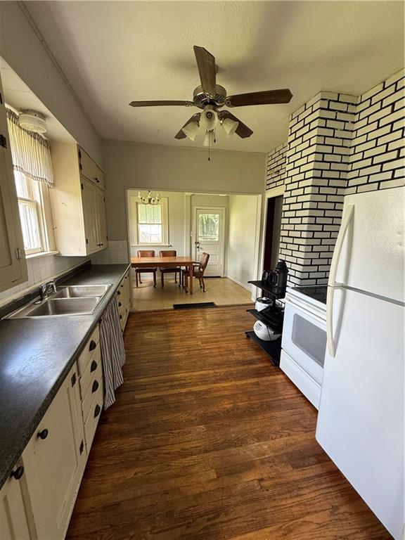 211 N Mulberry St, Maryville, MO 64468 - kitchen featuring white appliances, a ceiling fan, dark countertops, and dark wood-style floors