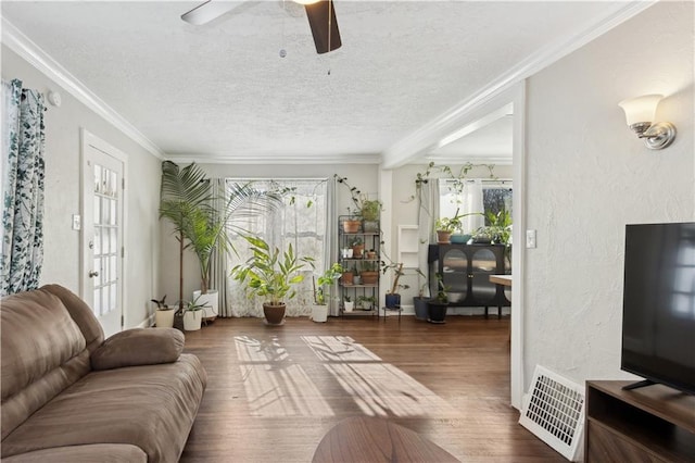 living room with ceiling fan, dark hardwood / wood-style flooring, ornamental molding, and a textured ceiling