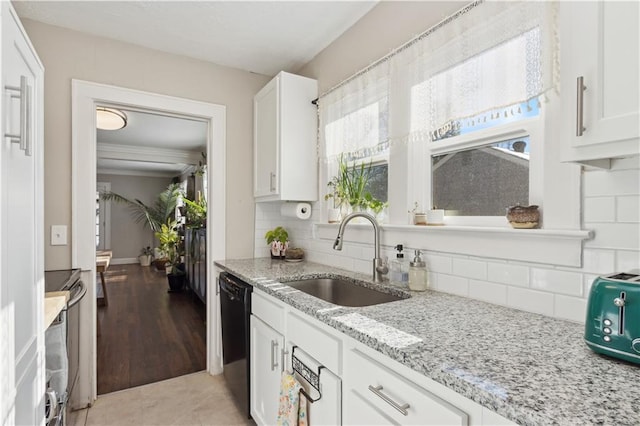 kitchen with light stone countertops, white cabinets, black dishwasher, decorative backsplash, and sink