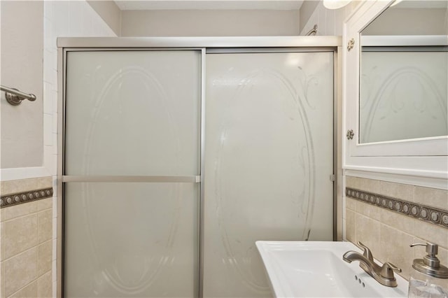 bathroom featuring sink, tile walls, and a shower with door