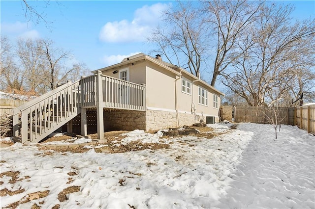 snow covered property with central air condition unit and a wooden deck