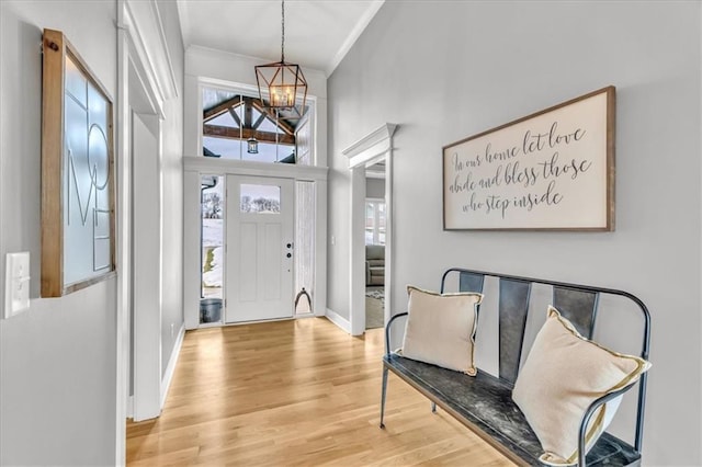 foyer entrance with a chandelier, crown molding, light hardwood / wood-style floors, and plenty of natural light