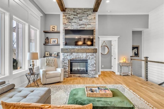 living room featuring beam ceiling, a stone fireplace, and hardwood / wood-style flooring