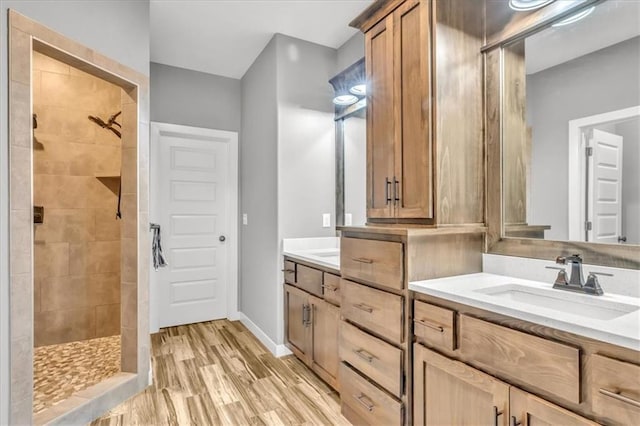 bathroom with vanity, wood-type flooring, and tiled shower