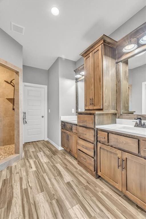 bathroom featuring hardwood / wood-style flooring, vanity, and tiled shower