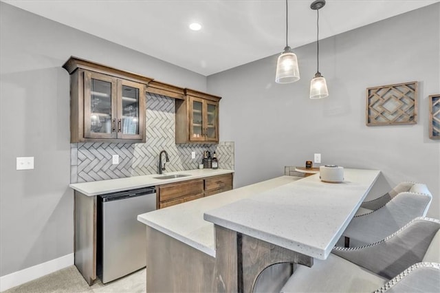 kitchen with dishwashing machine, sink, a breakfast bar, tasteful backsplash, and decorative light fixtures