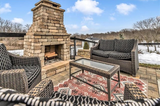 snow covered patio with an outdoor stone fireplace