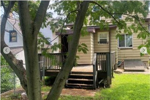 back of property with a wooden deck and a lawn